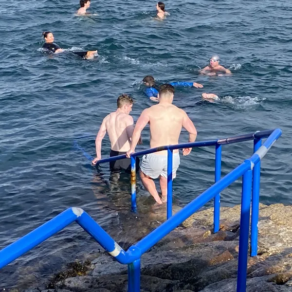 2 men walking into water to join larger group